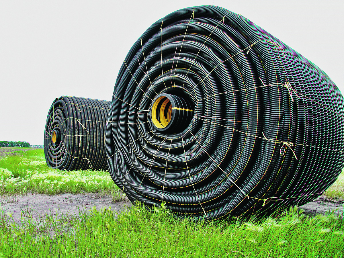 Two large rolls of tile drainage tubing sit in a field ready to be installed.