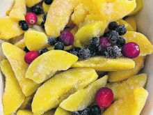 Sliced peaches and a variety of whole berries in a bowl.