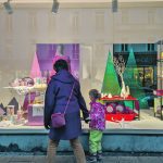 A mother holds the hand of her young daughter as they look into a store's window display in Munich.