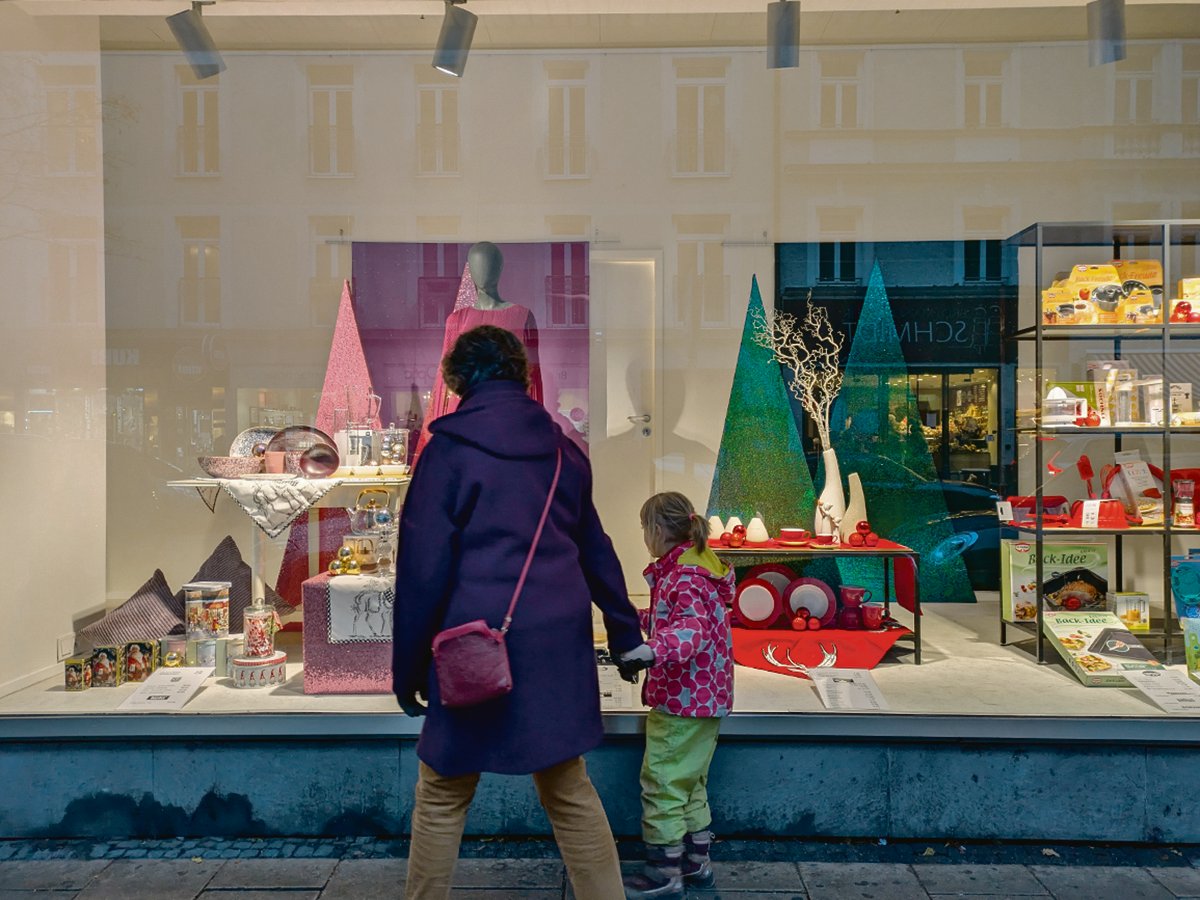 A mother holds the hand of her young daughter as they look into a store's window display in Munich.