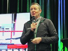Tom Wolf speaks into a microphone during a presentation at the 2025 Crop Production Show in Saskatoon.
