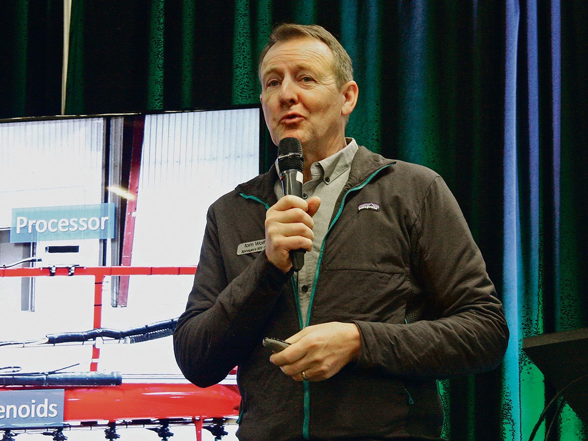 Tom Wolf speaks into a microphone during a presentation at the 2025 Crop Production Show in Saskatoon.