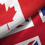 A Canadian flag and a U.K. flag beside each other on a table.