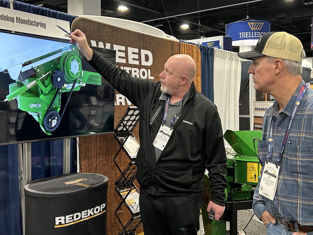 Trevor Thiessen of Redekop Manufacturing explains the company’s straw chopper to a farmer from Oregon at the Commodity Classic in Denver, Colorado, March 4.