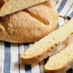 Portuguese cornbread, sliced, on top of a blue and white striped tablecloth.
