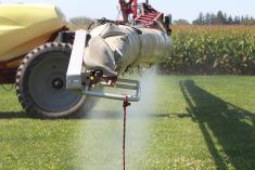 Fine mist drops from the spray bar of a sprayer onto a crop.