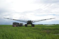 A large modern high-clearance sprayer is parked in a field next to its support truck.