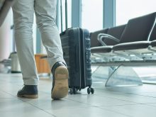 A low-level photo of a traveller's shoes as they walk through an airport.