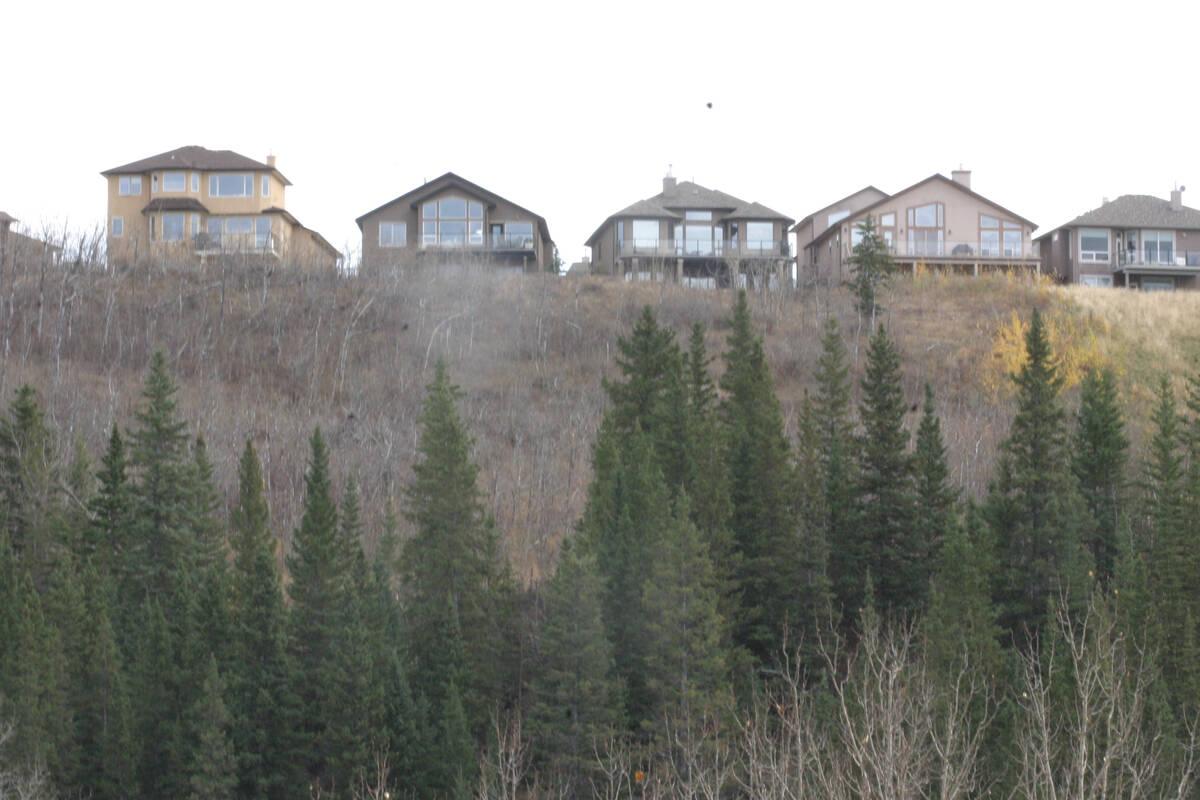 Expensive homes sit on a hill with a scenic view of the valley beneath them.