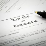 Close-up of a "Last Will and Testament of" document with a pen sitting on top of it.