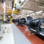 Car bodies move along an assembly line in a very modern factory.