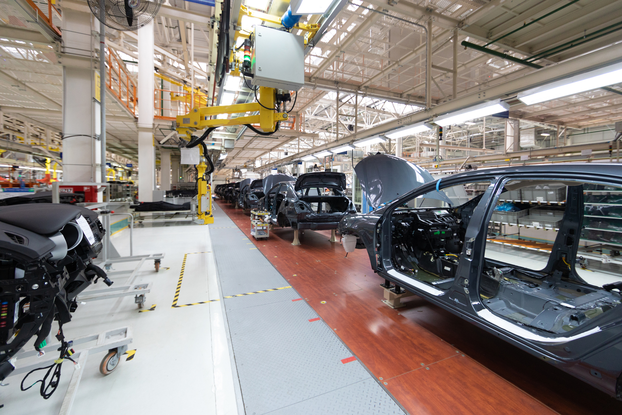 Car bodies move along an assembly line in a very modern factory.