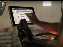 A farmer uses a touchscreen in the cab of a farm vehicle.