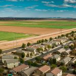 An aerial photo showing the houses in a suburban neighbourhood right across the road from agricultural land.