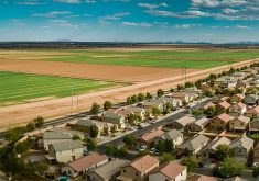 An aerial photo showing the houses in a suburban neighbourhood right across the road from agricultural land.