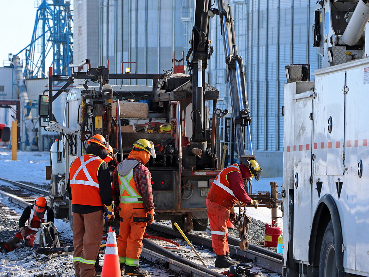 Rail workers work on the tracks next to an inland grain terminal.