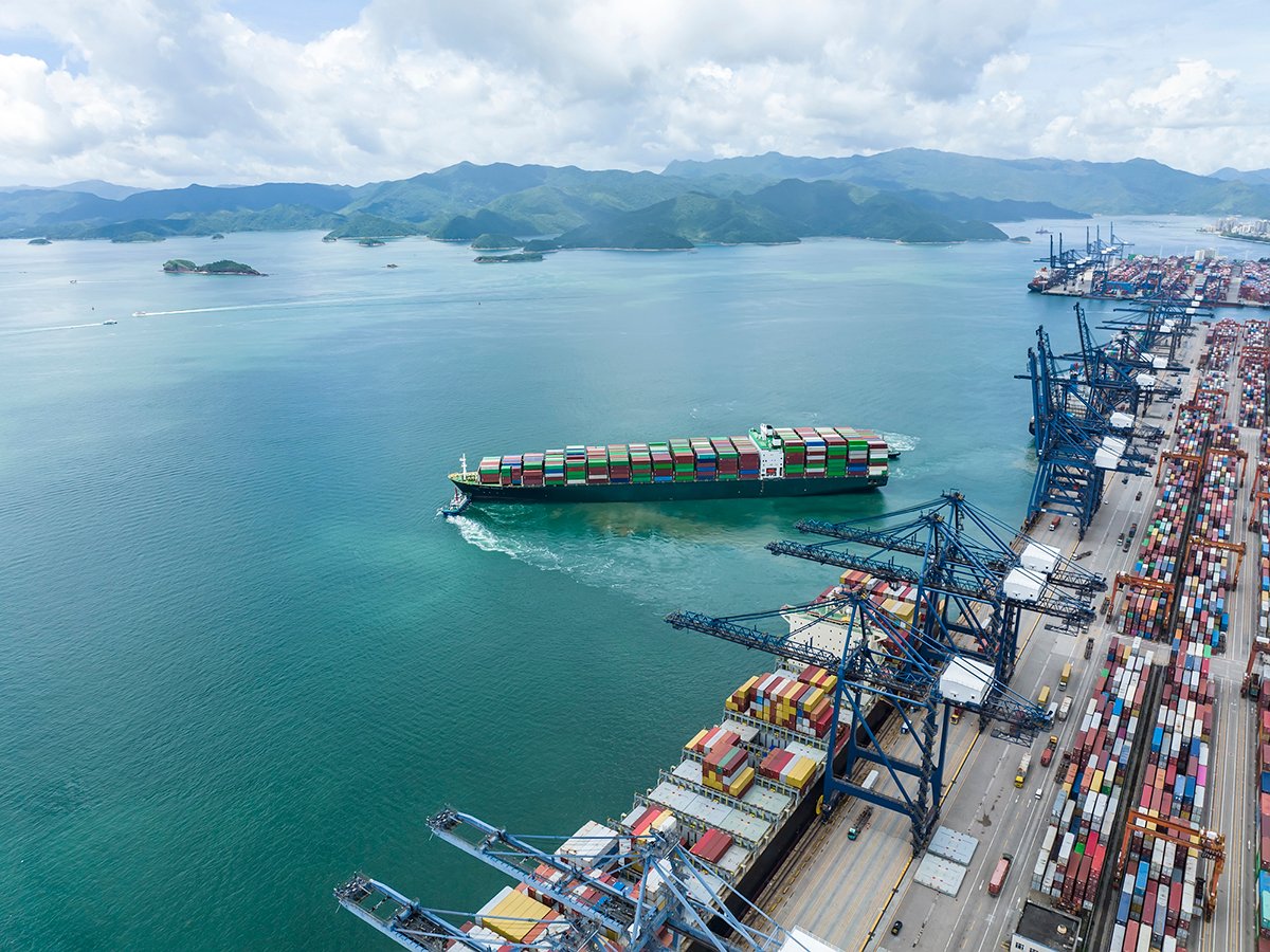 A large, fully-loaded container ship leaves the dock at a busy container port in China.