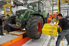 An assembly line worker tightens the lug nuts on the front tire of a Fendt tractor at an assembly plant in Germany.
