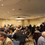People sit at tables in a large meeting room during the Sask. Ag. Summit 2025.