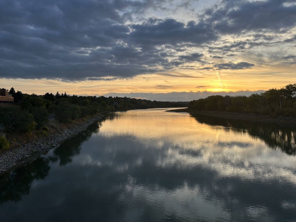 Looking up-river at sunset with the sky and its clouds reflected in the calm surface of the water.