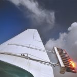 The wing of an aircraft with several burning "tubes" dispersing silver iodide - otherwise known as "cloud seeding."