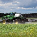 A sprayer sprays canola ahead of bolting.