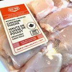 Chicken thighs on a white styrofoam tray, wrapped in plastic, at a Co-Op grocery store.