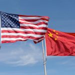 An American and a Chinese flag fly side by side.