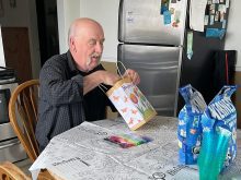 Henk Van Essen sits at his kitchen table looking at a gift bag with several other bags awaiting his attention.