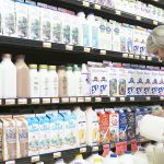 A woman looks at dairy items in a grocery store.
