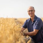Aaron Beattie, an oat and barley breeder at the University of Saskatchewan’s Crop Development Centre, poses for a photo in a ripe field of oats.