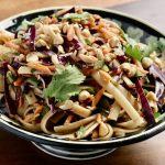 A pasta salad sits in a bowl on a table.