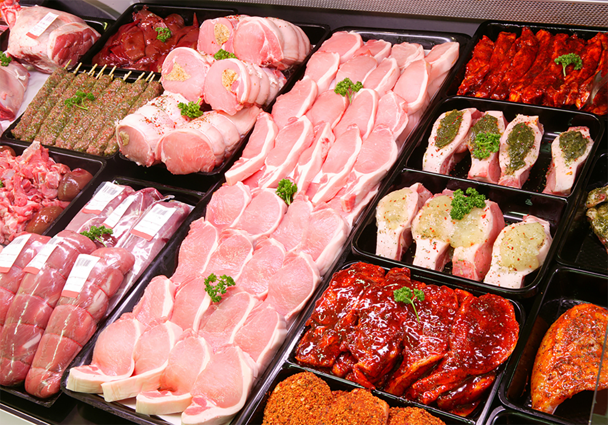 Various pork meat products are on display in a butcher shop.