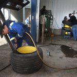 Two farm workers work on implement tires in a shop during seeding.