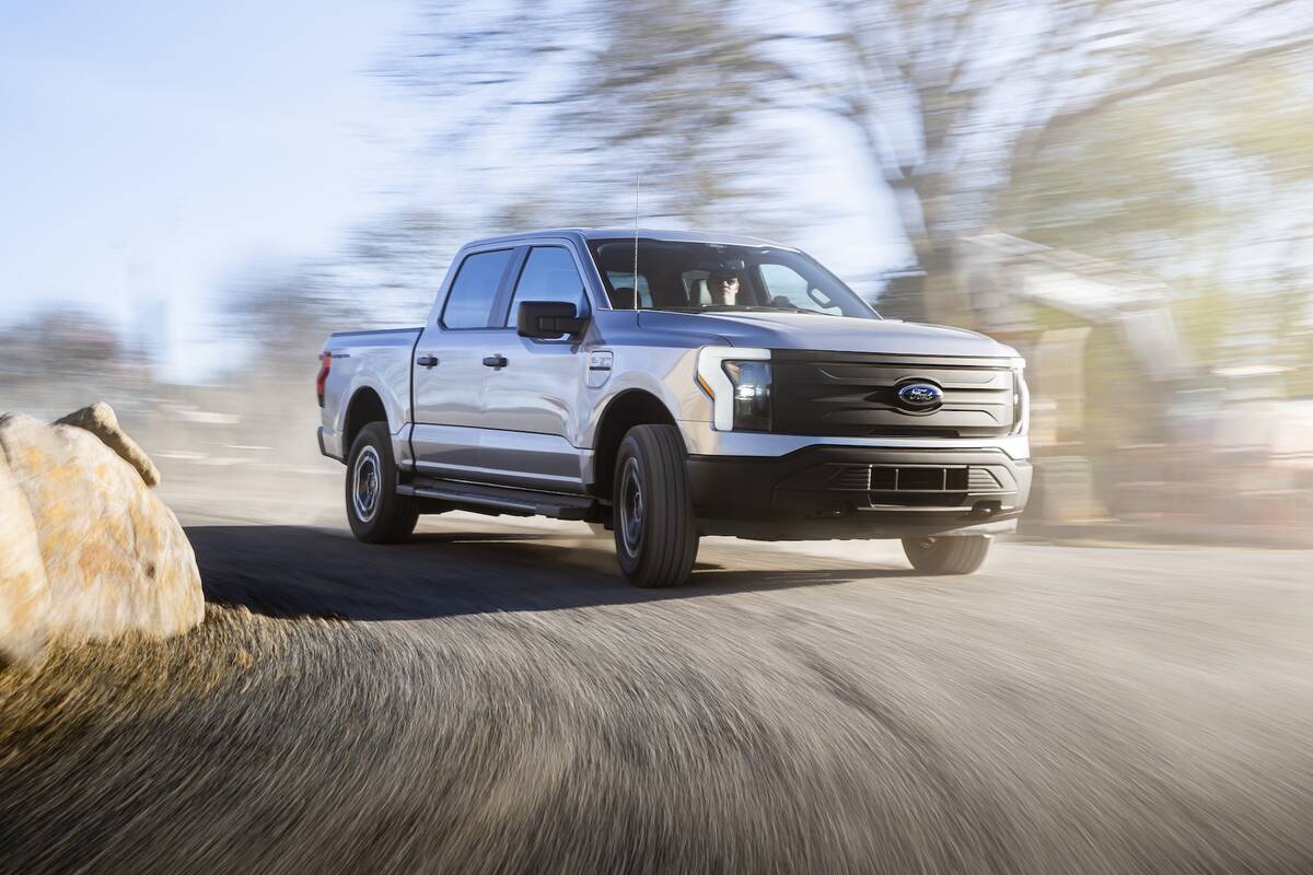 A promotional "action" photo of a Ford F150 Lightning EV rounding a curve on a gravel/dirt road.