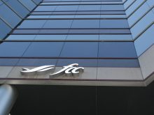 Looking upward at a tall, blue building with an Farm Credit Canada (FCC) logo on it.