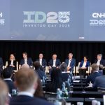 Nine men and women in business suits sit in identical chairs on a stage under a banner that reads, "CNH ID25 Investor Day 2025."