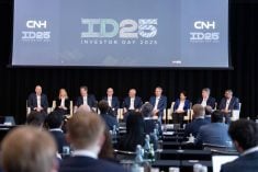 Nine men and women in business suits sit in identical chairs on a stage under a banner that reads, "CNH ID25 Investor Day 2025."