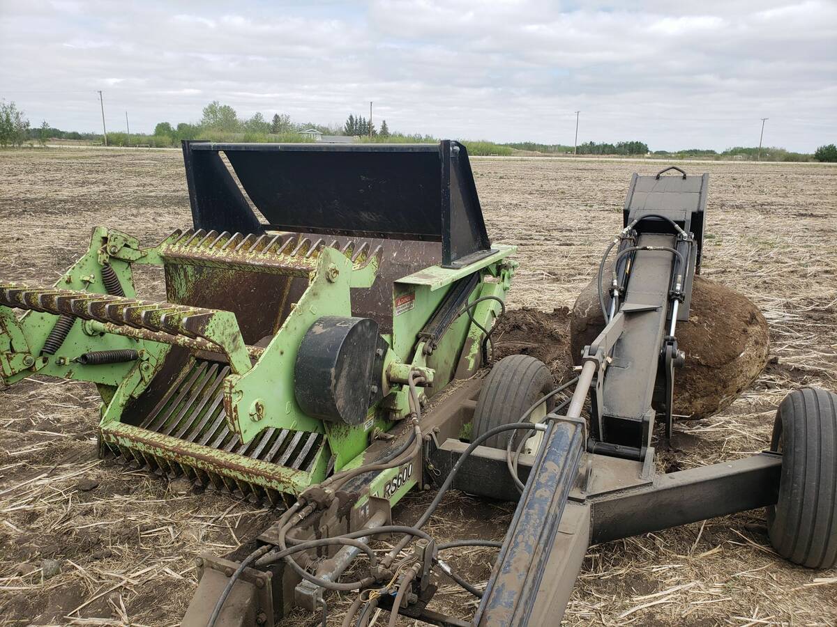 Photo of a farmer-made rock digger that mounts to the side of a commercial rock picker and is capable of dealing with larger, partially buried rocks.