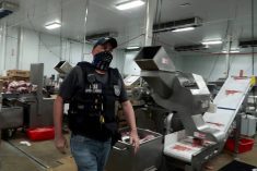 An agent passes meat being prepared during a raid by U.S. Immigration and Customs Enforcement (ICE) at a Glenn Valley Foods meat production plant in Omaha, Nebraska, U.S. June 10, 2025 in a still image from video. Photo: U.S. Immigration and Customs Enforcement/Handout via Reuters.
