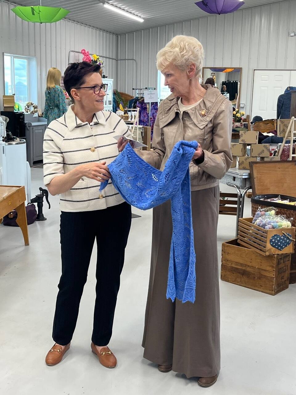 Master knitter Mariette Anderson, from Gravelbourg, Sask., presents the scarf she designed and knit for Queen Camilla to Lt.-Gov. Bernadette McIntyre during a visit to the Canadian Fibre Mill at Caron, Sask.