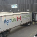 A semi trailer belonging to AgraCity is backed up to the loading dock at an AgraCity warehouse.