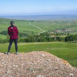 A woman stands near the edge of a valley, looking over the Reesor Ranch from a hike into the hills.
