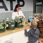 Barbara Hodecker, director of research and development for ATP Nutrition shows youth Blair and Eleanor Uruski how biostimulants help plants handle abiotic stress like drought.