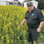 Western Producer Markets Desk analyst Bruce Burnett inspects a canola plot at Ag In Motion 2025.