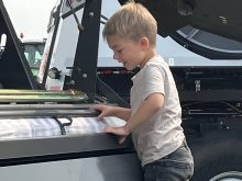 Three-year-old Liam Hrappstead gets a closer look at a Massey Ferguson round baler at Ag in Motion 2025.