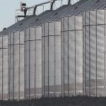 A row of six massive steel grain bins.
