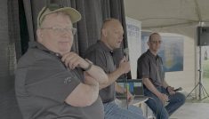 Bruce Burnett, left, Jerry Klassen and Ranulf Glanville talk markets at the Ag in Motion farm show near Langham, Sask.
