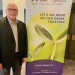 Barry Senft, CEO of Seeds Canada, poses next to a Seeds Canada banner.