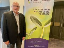 Barry Senft, CEO of Seeds Canada, poses next to a Seeds Canada banner.